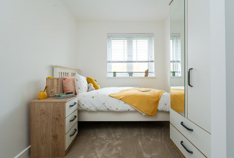 A bedroom with a bed, bedside table, and wardrobe.