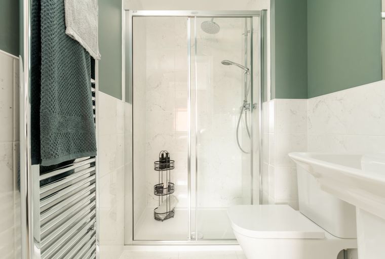 A bathroom with a shower, toilet, sink, and towel warmer.