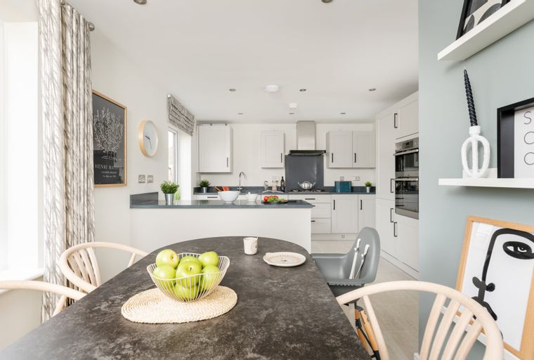 A modern kitchen and dining area with white cabinets, a kitchen island, and a dining table with chairs.