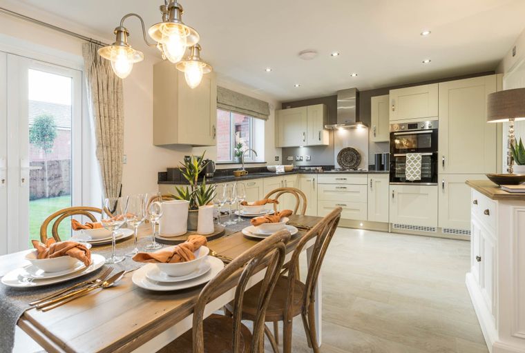 A dining table set for a meal in a kitchen with light-colored cabinets and appliances.