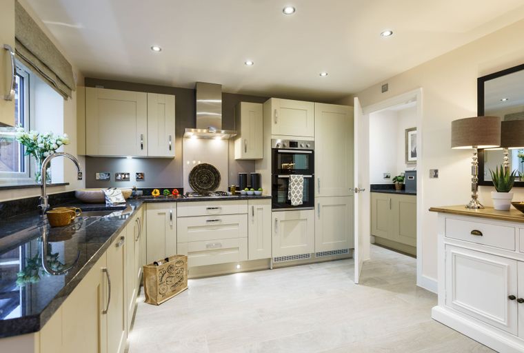 A kitchen with cream cabinets, a granite countertop, and modern appliances.