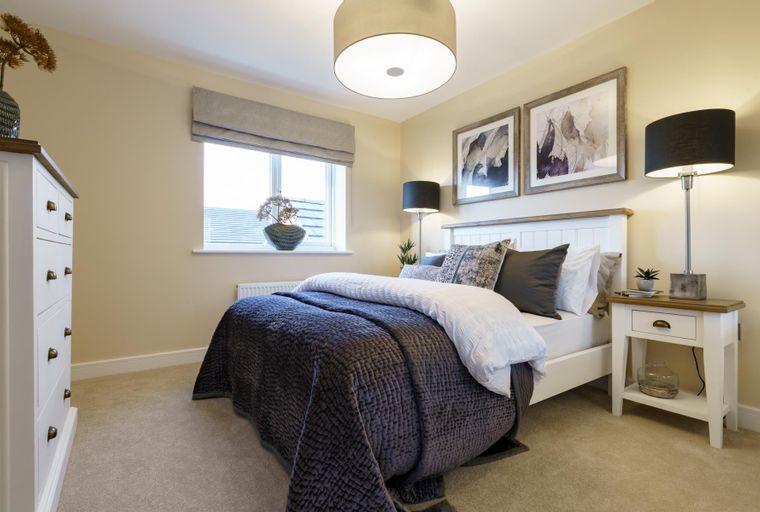 A bedroom with a bed, nightstands, and a window.