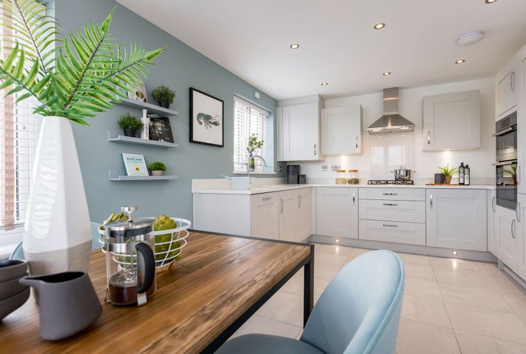 A modern kitchen with white cabinets, a wooden dining table, and a blue chair.