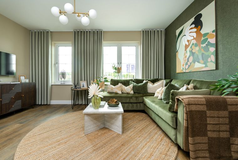 A living room with a green sectional sofa, coffee table, rug, and artwork.