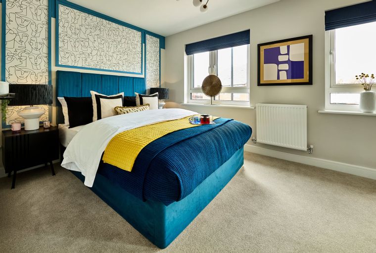 A bedroom with a bed, pillows, blankets, and a nightstand.