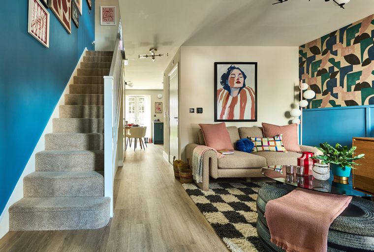 A living room and hallway with a staircase, sofa, coffee table, and dining area visible.