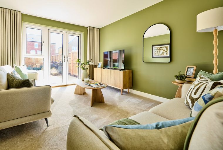 A living room with two sofas, a coffee table, a television, and double doors leading outside.