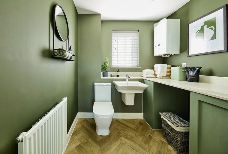 A bathroom with a toilet, sink, mirror, and radiator.