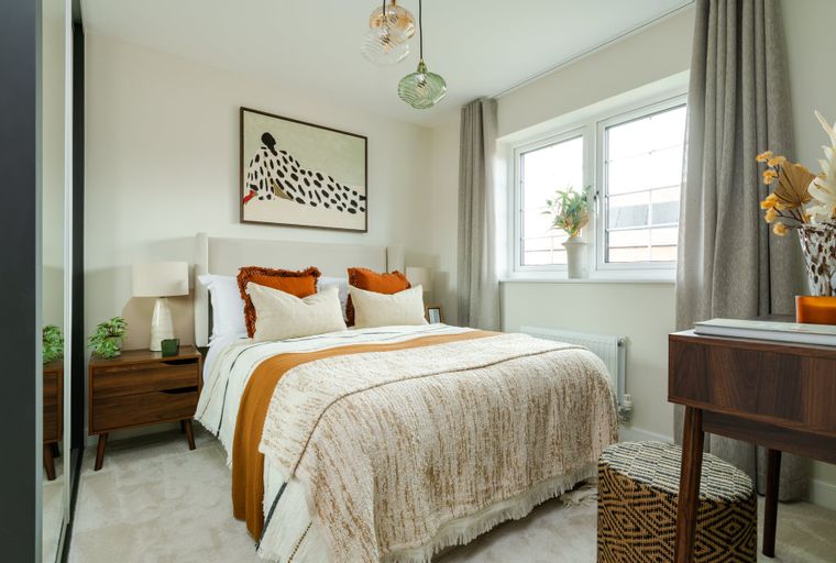 A bedroom with a bed, bedside tables, a window, and a desk.