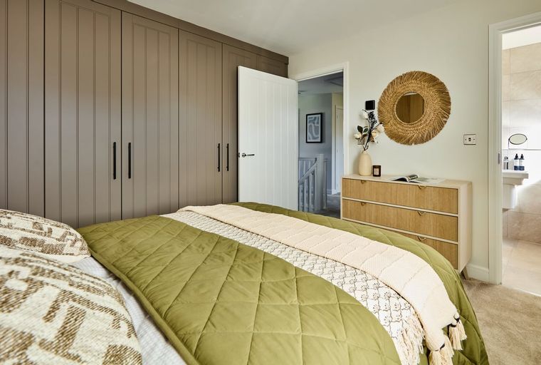 A bedroom with a bed, a wardrobe, and a dresser.