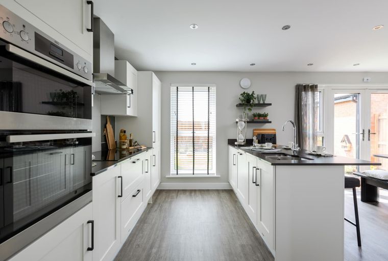 A modern kitchen with white cabinets, a black countertop island, and a large window.