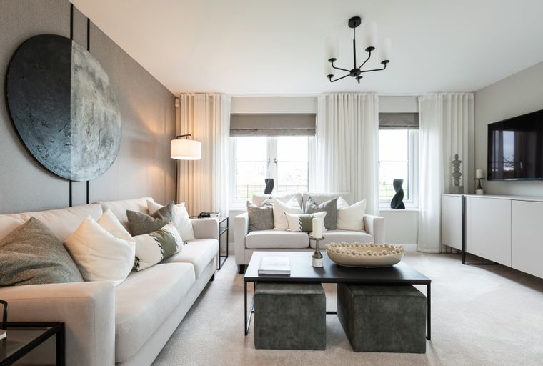 A living room with two sofas, a coffee table, and a large circular artwork on the wall.