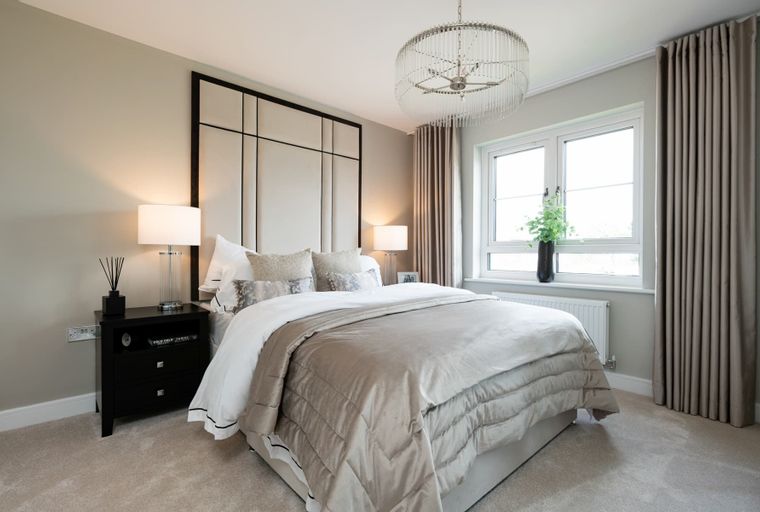 A bedroom with a bed, bedside tables, lamps, and a window.