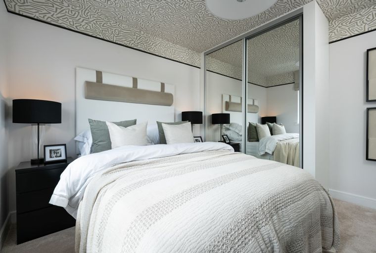A bedroom with a bed, nightstand, and mirrored wardrobe.