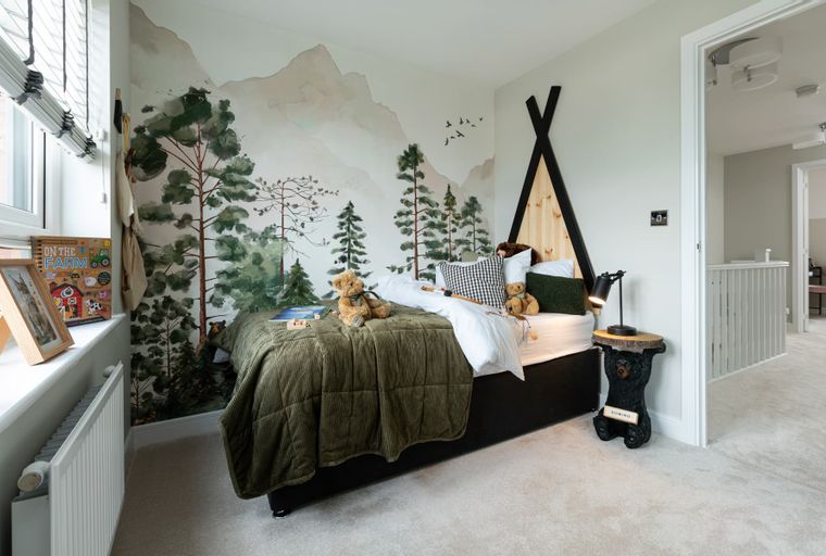 A children's bedroom with a bed, teddy bears, and a forest mural.
