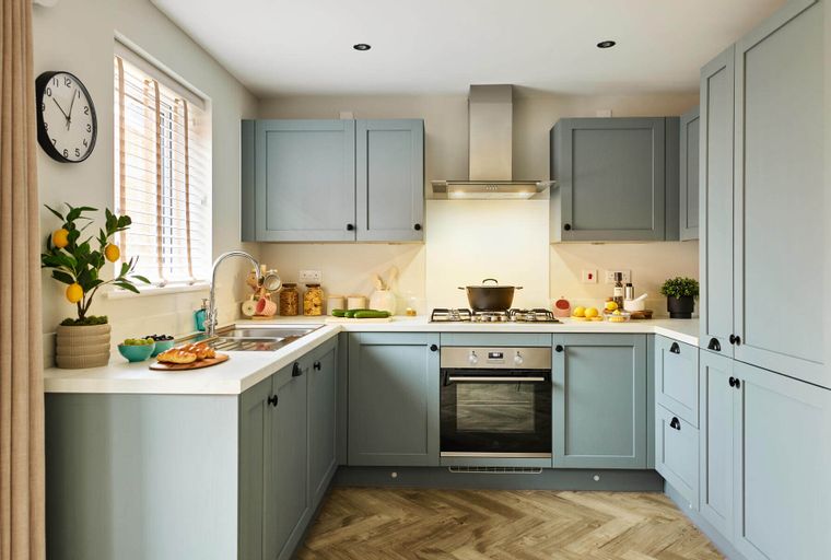 A kitchen with light blue cabinets, a stainless steel range hood, and a gas stovetop.