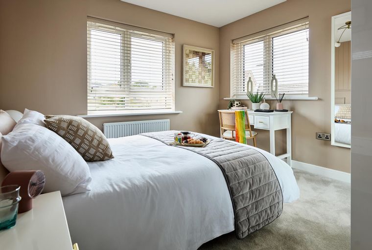 A bedroom with a bed, breakfast tray, vanity desk, and chair.