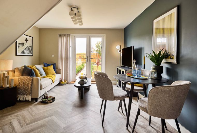 A living and dining room with a sofa, coffee table, dining table, chairs, and a television.