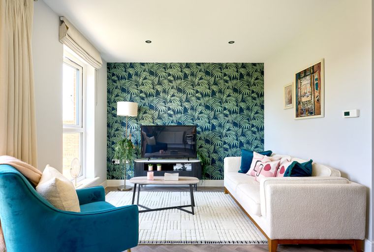 A living room with a sofa, armchair, coffee table, and a TV on a stand.