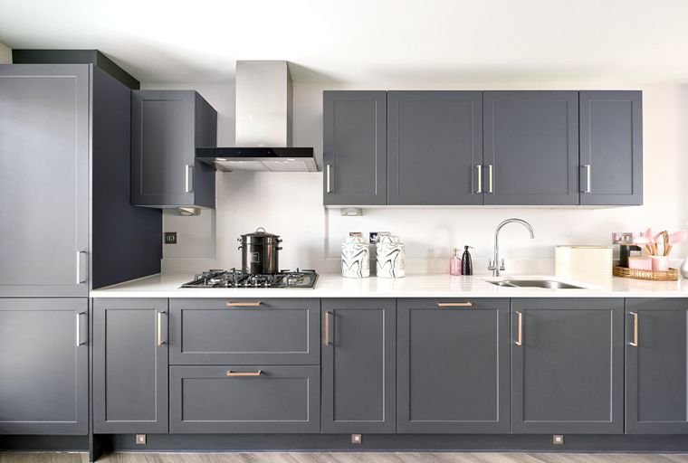 A modern kitchen with dark gray cabinets, a gas hob, and a sink.