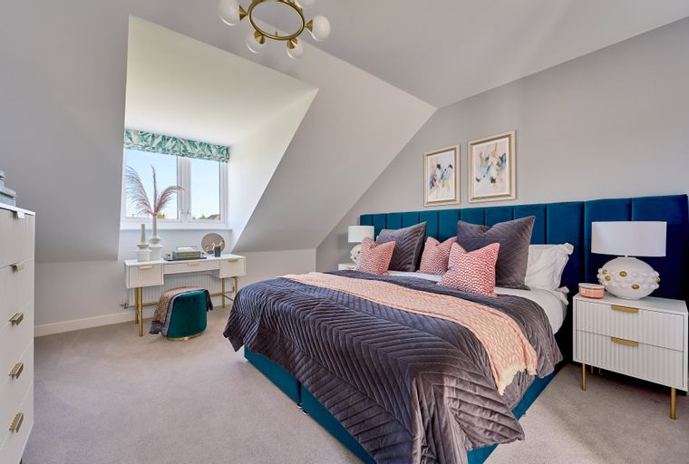 A bedroom with a bed, a vanity, and a window.