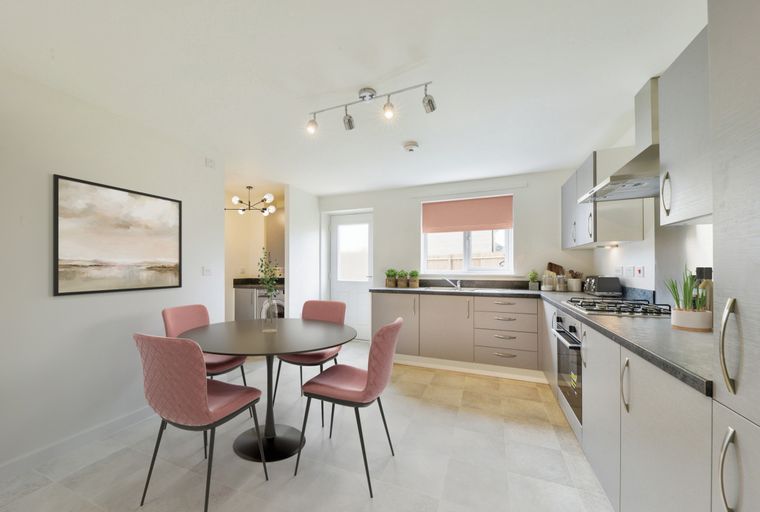 A kitchen and dining area with pink chairs around a table and grey cabinets.