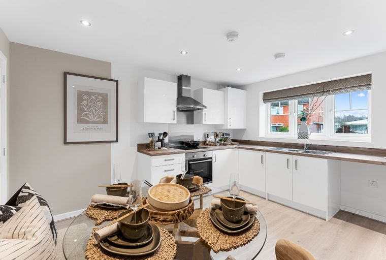 A dining area and kitchen with white cabinets, a dining table, and a window.