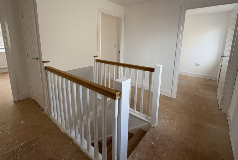 A landing with a staircase and doorways leading to rooms.