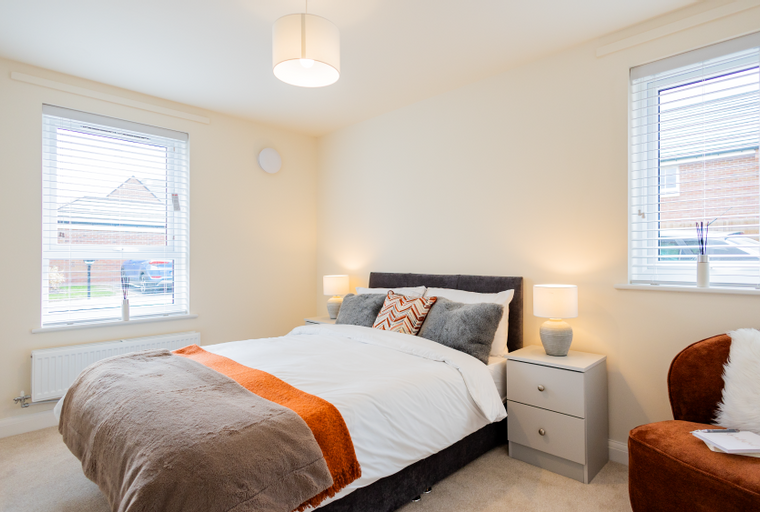 A bedroom with a bed, bedside tables, lamps, and a chair.