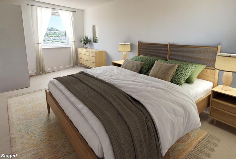 A bedroom with a bed, pillows, a dresser, and a nightstand.