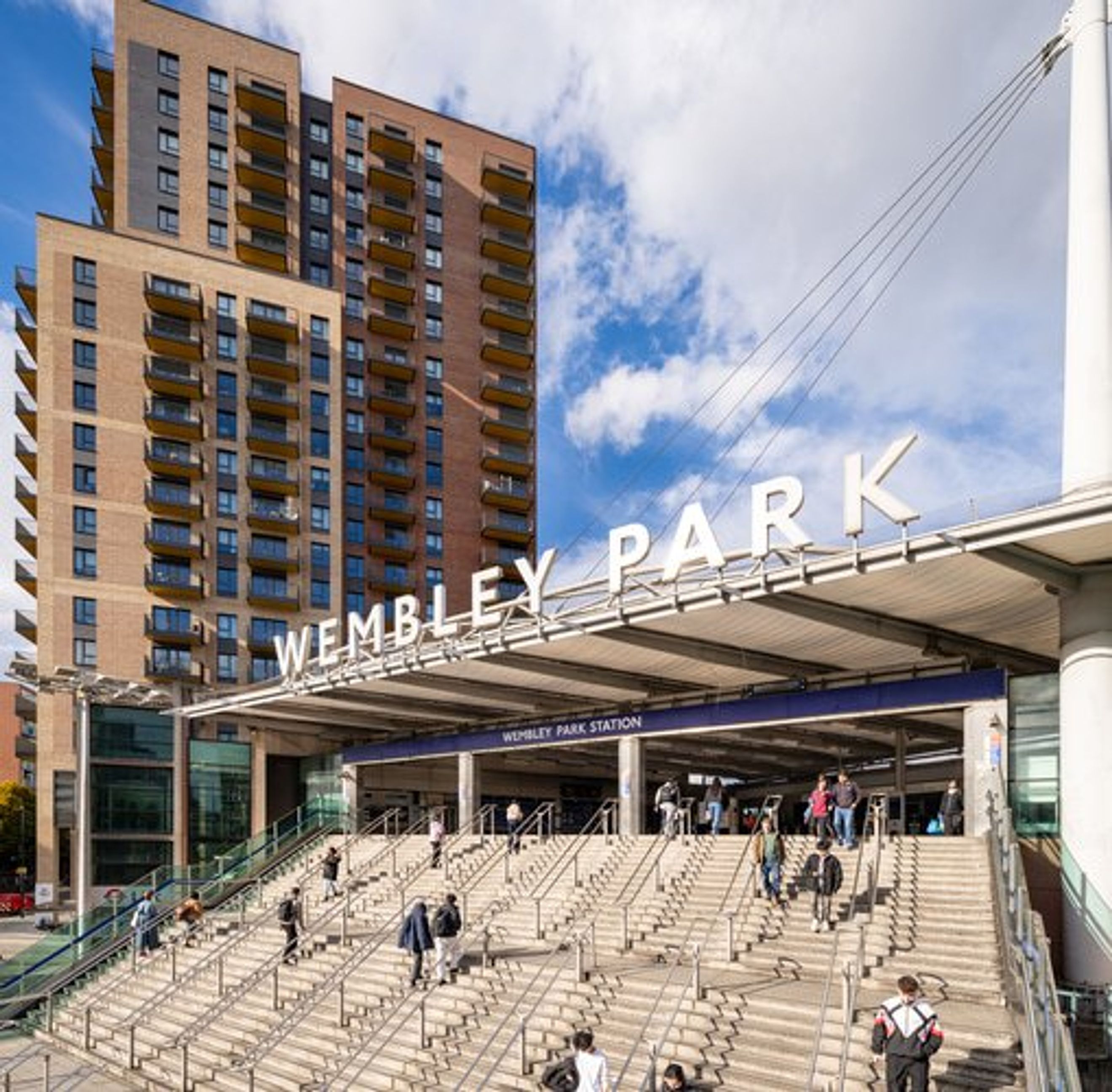 A view of the Wembley Park Station entrance with a modern apartment building in the background.