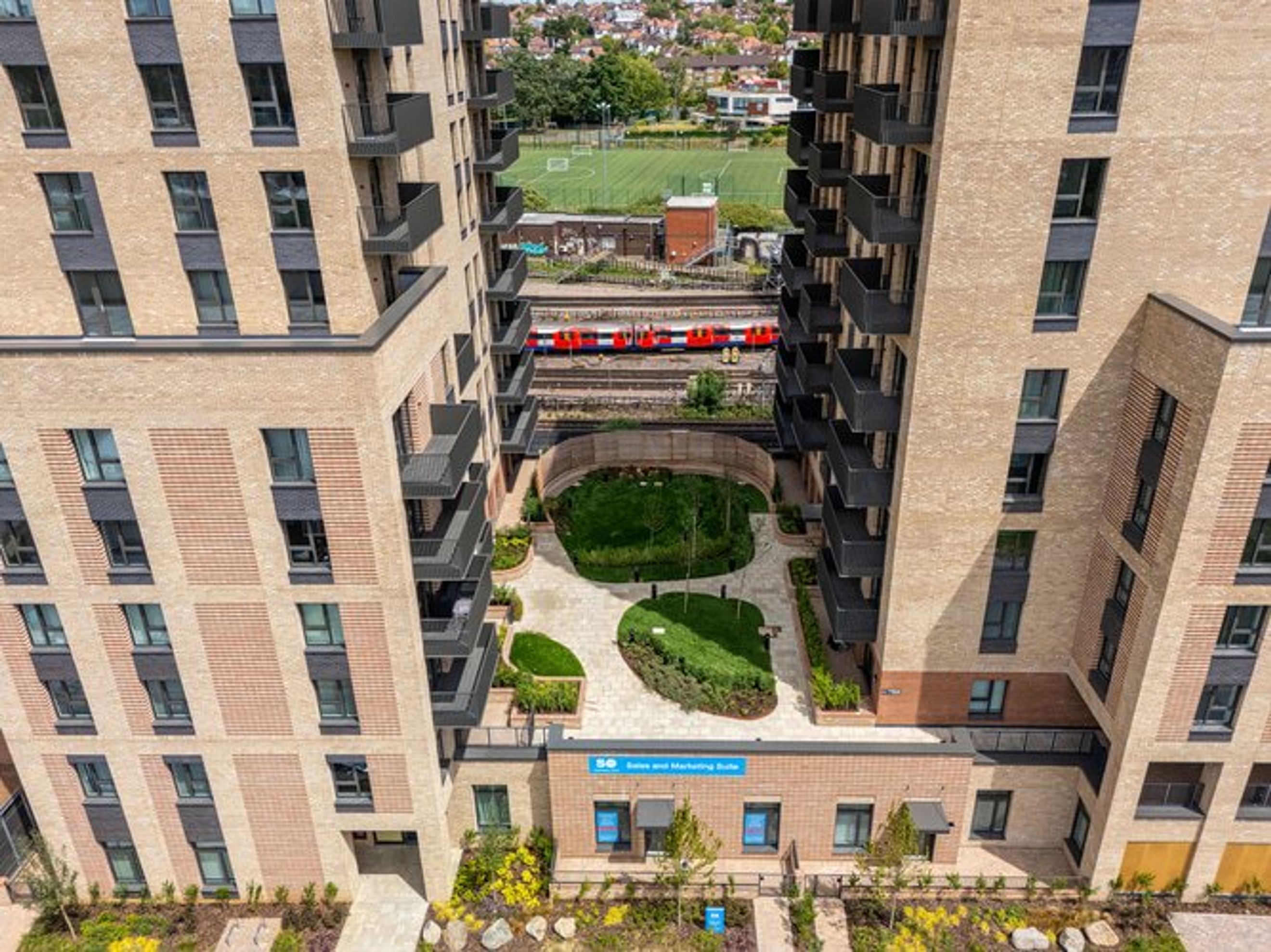 A view of a modern apartment complex with a train passing by in the background.
