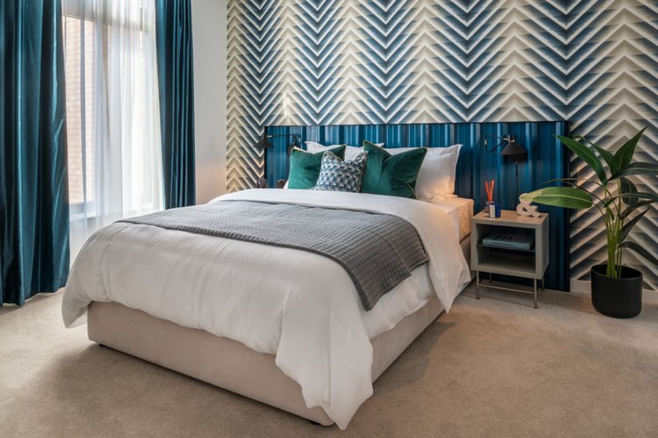 A bedroom with a bed, pillows, curtains, and a nightstand.