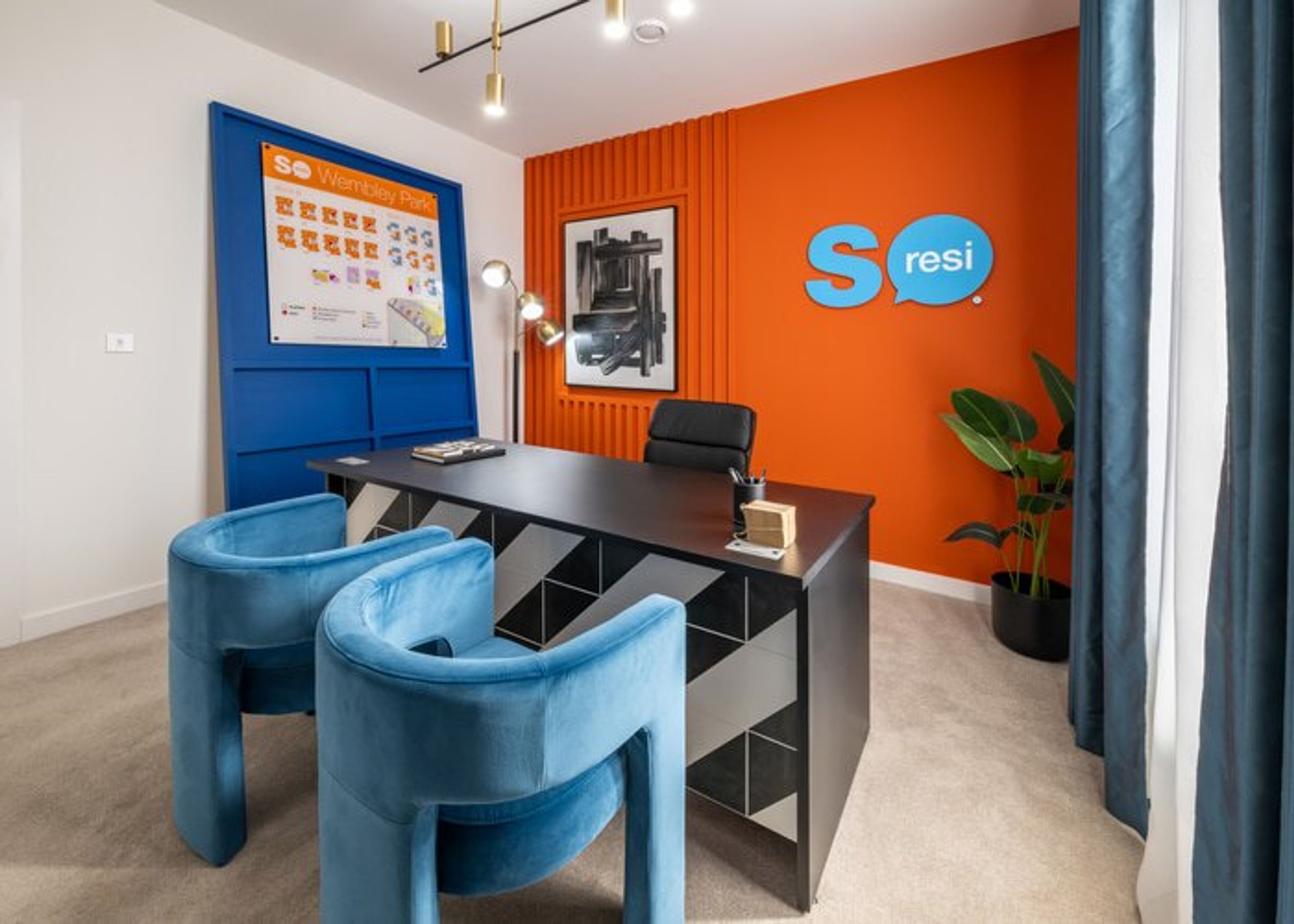 A modern office space with a desk, chairs, and a poster on the wall.