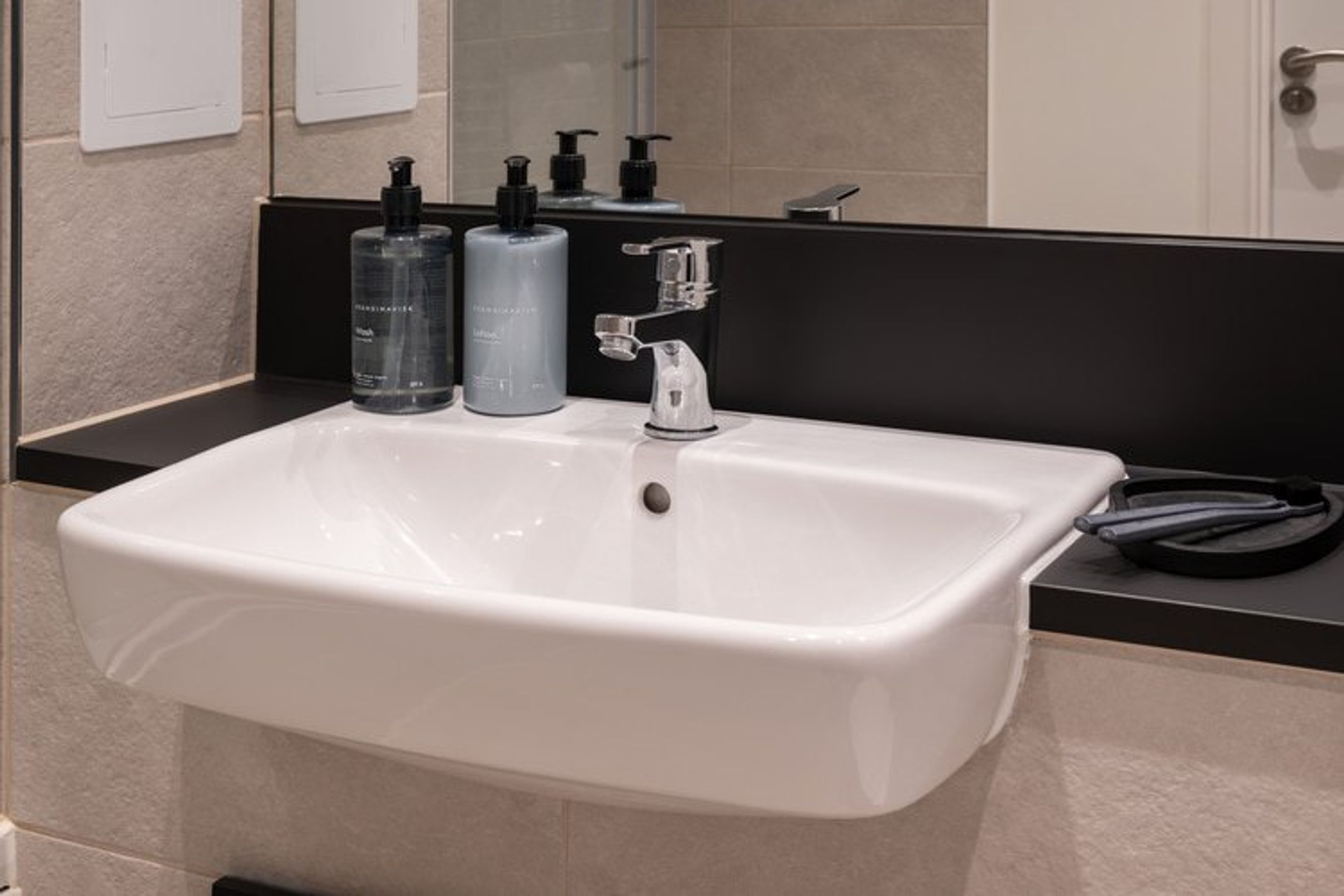 A bathroom sink with two soap dispensers, a faucet, and a toothbrush holder.