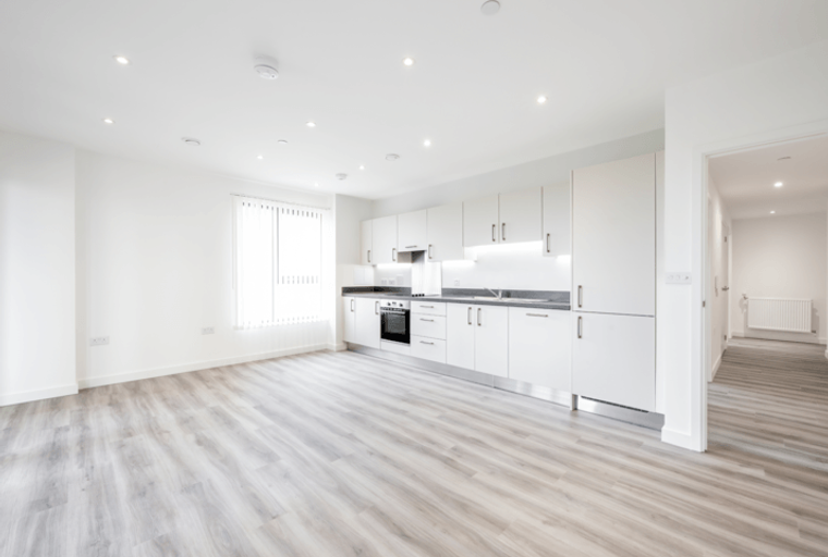 A modern kitchen and living area with white cabinets and light wood-effect flooring.