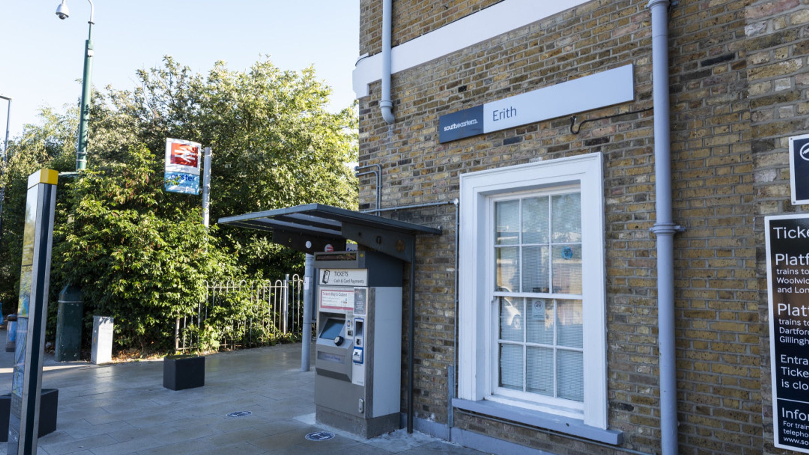 A train station platform with a ticket machine and signage for Erith station.
