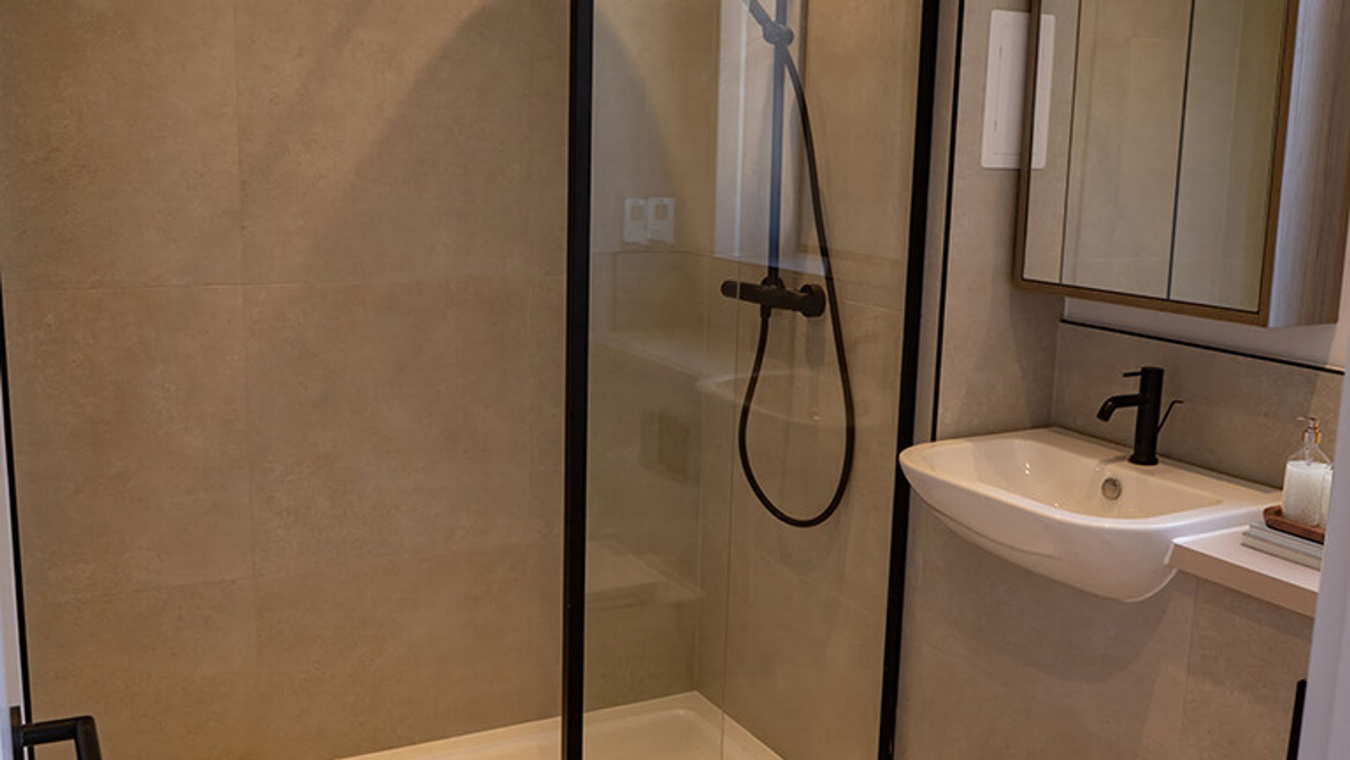 A bathroom with a walk-in shower, a sink, and a medicine cabinet.