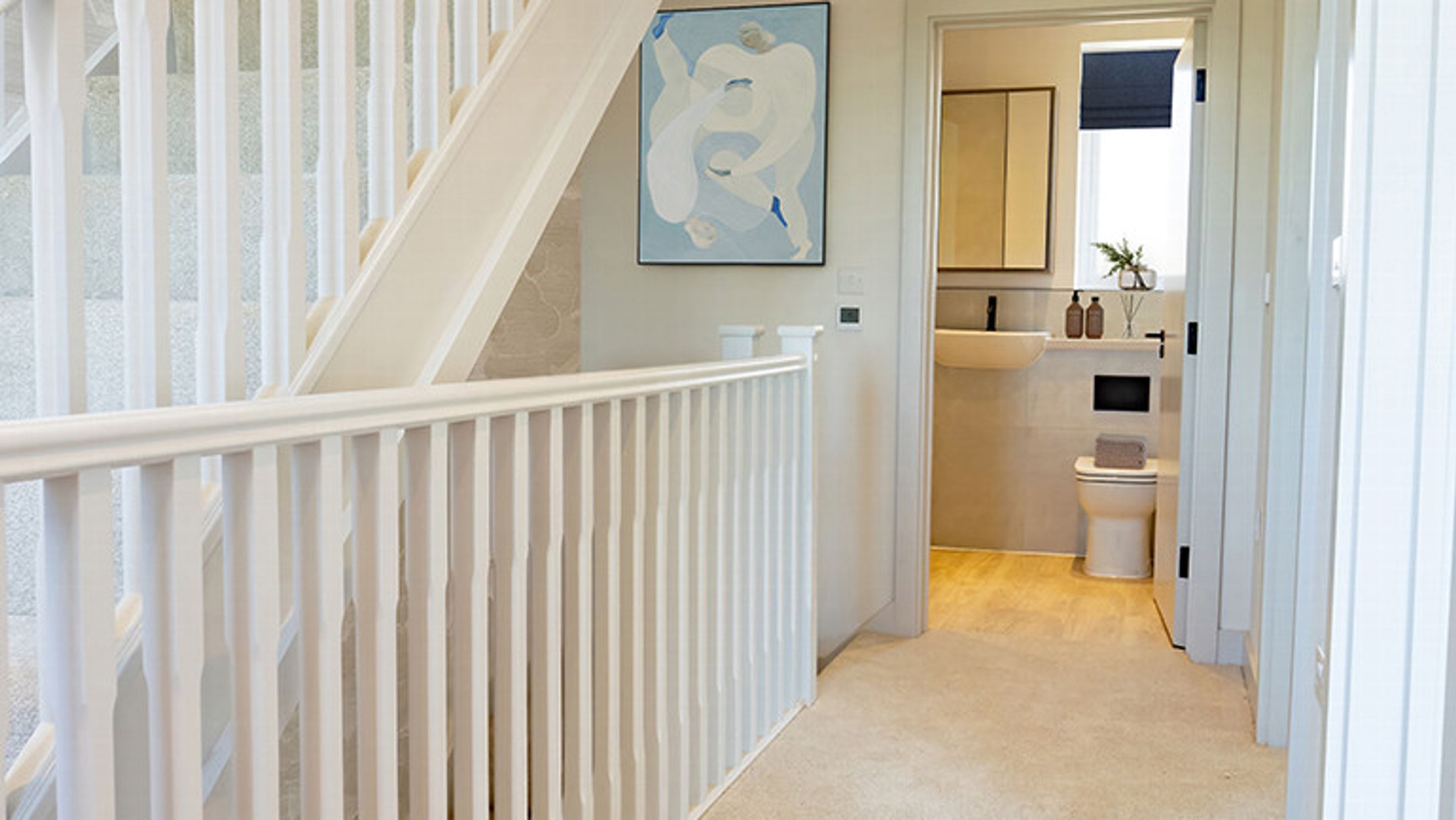 A hallway with a staircase and a doorway leading to a bathroom.