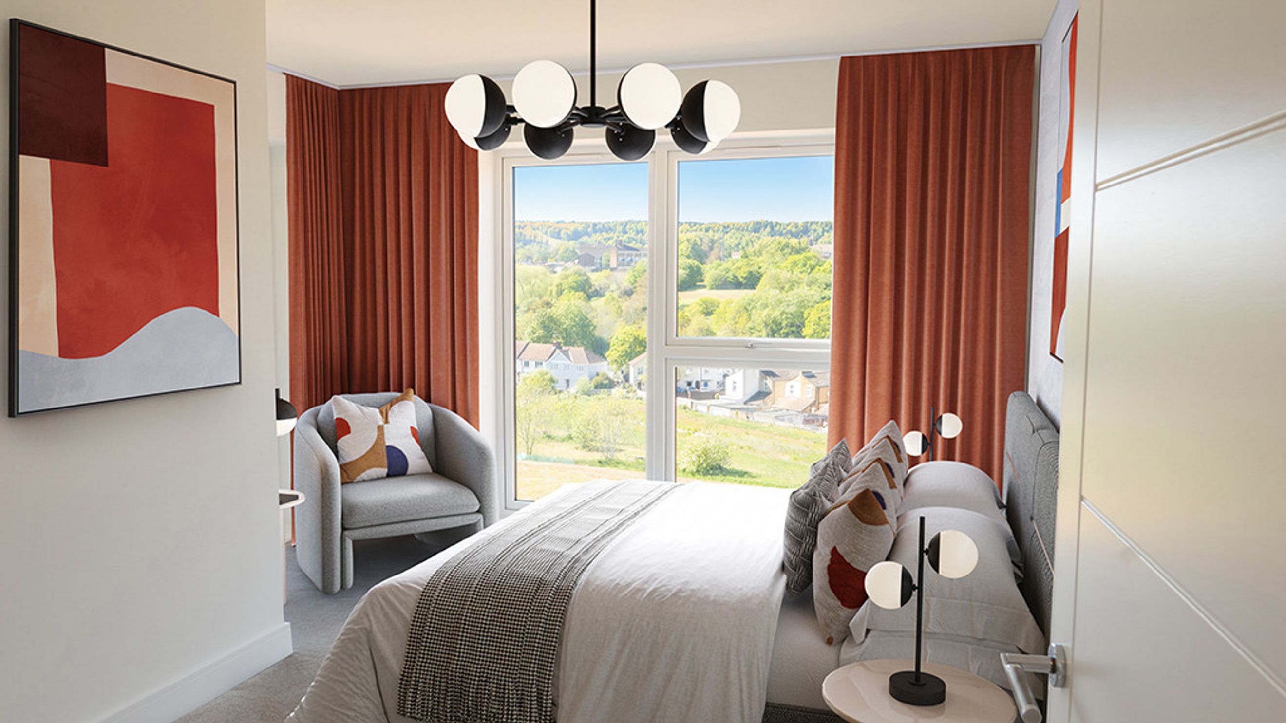 A bedroom with a bed, armchair, and a large window overlooking a green landscape.