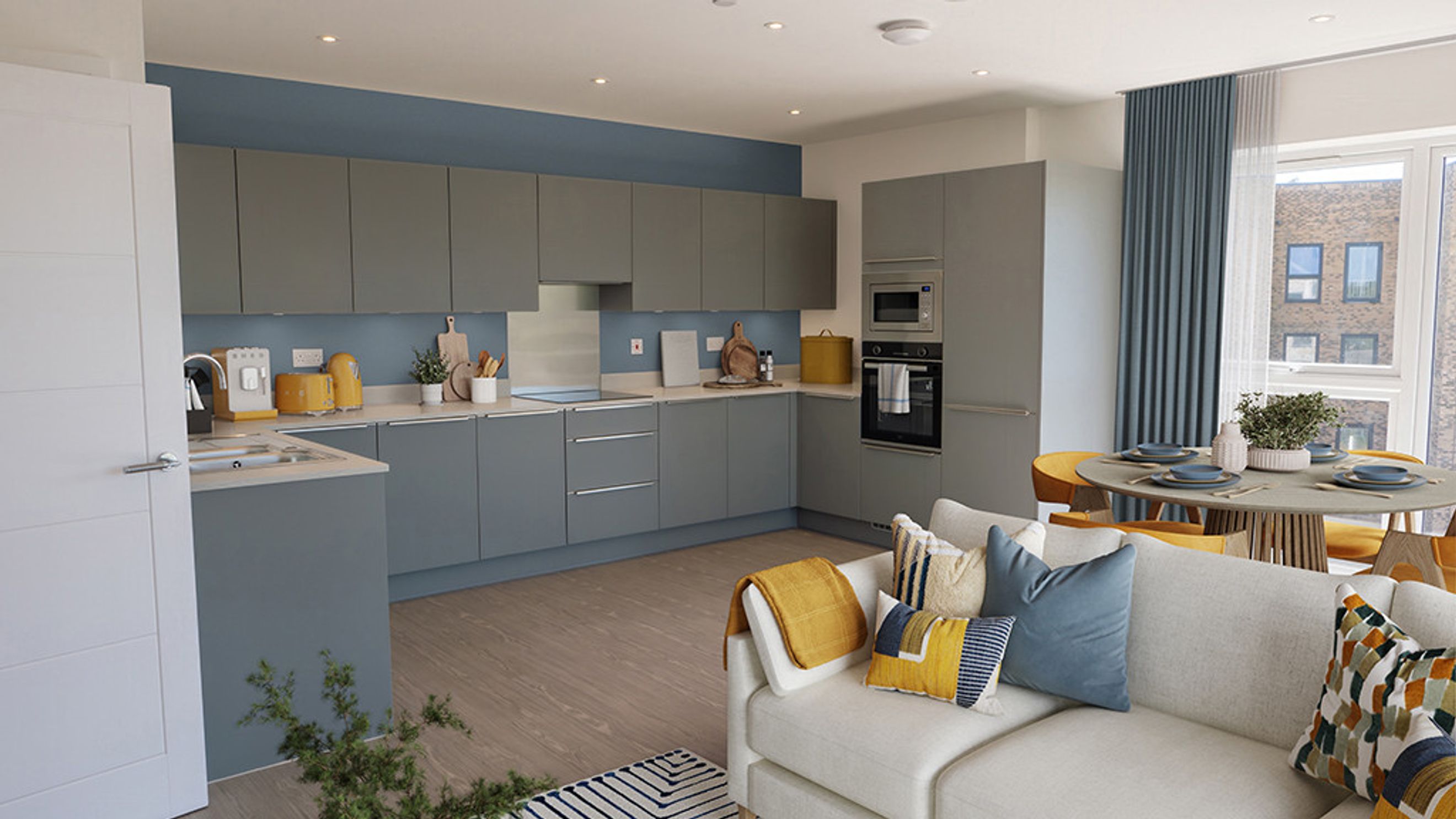 A modern kitchen and living area with grey cabinets, a dining table, and a sofa.