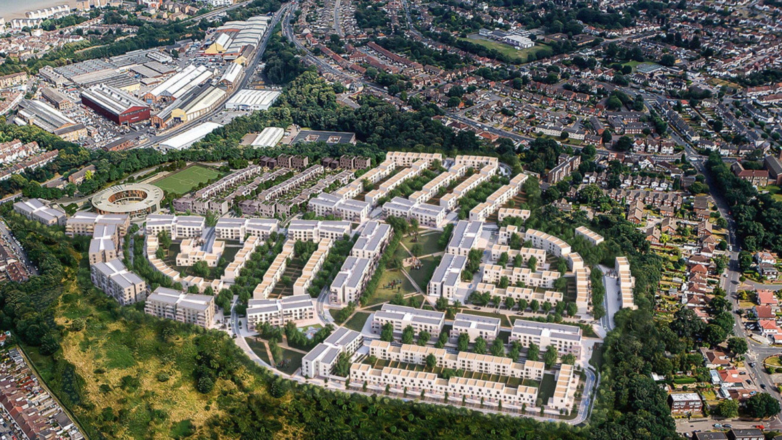 An aerial view of a modern housing development with apartment buildings and townhouses surrounded by trees and green spaces.