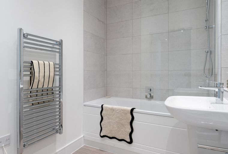 A bathroom with a bathtub, sink, and towel warmer.