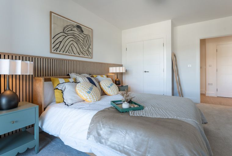 A bedroom with a bed, bedside tables, lamps, and artwork.