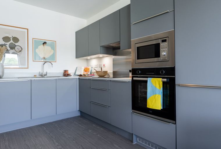 A modern kitchen with grey cabinets, a sink, and stainless steel appliances.