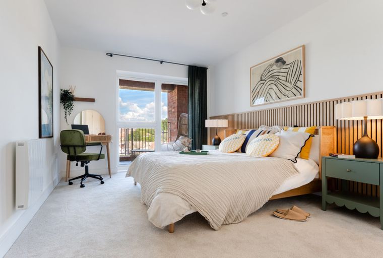 A bedroom with a bed, a desk, and a window.