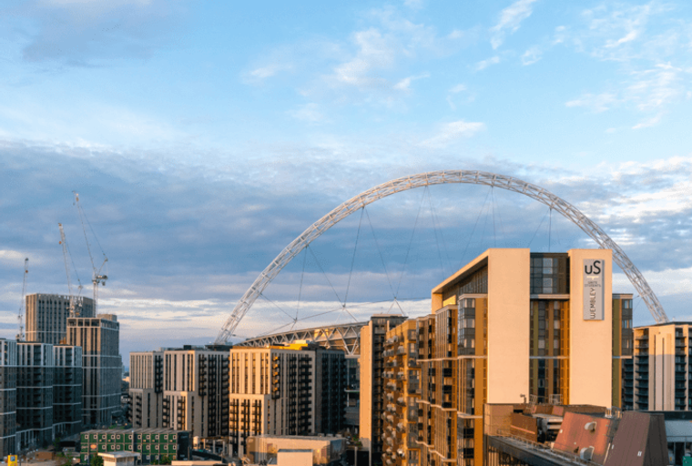 A view of modern apartment buildings with the Wembley Arch in the background.