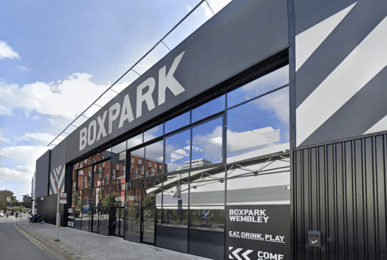A modern Boxpark Wembley building with large glass windows and prominent signage.