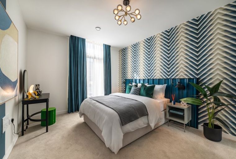A bedroom with a bed, accent wall, and curtains.