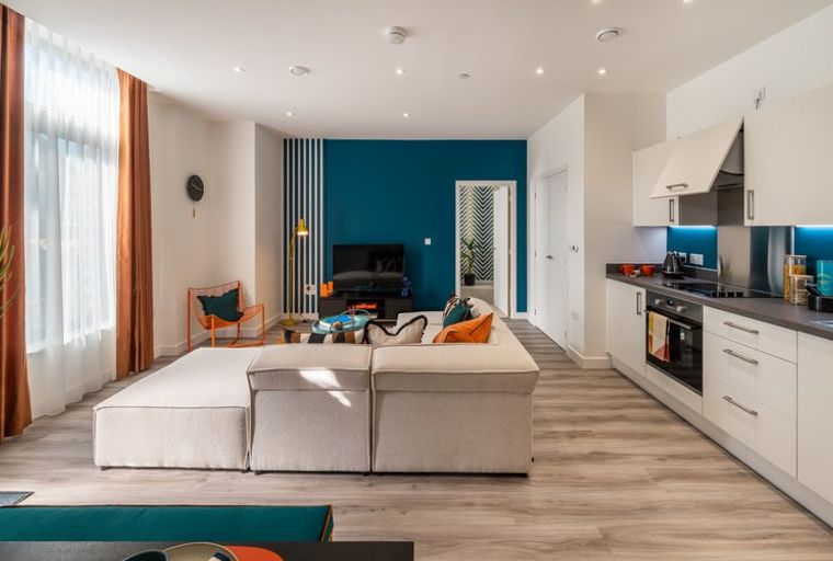 A living room and kitchen area with a sofa, television, and kitchen counter.